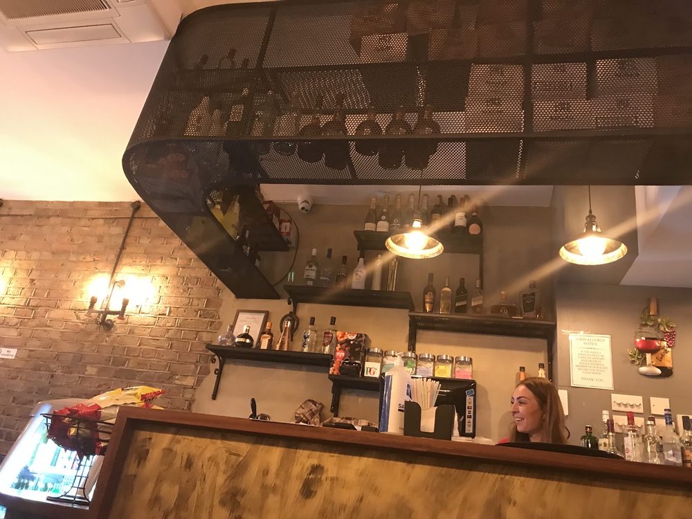 The counter and back bar, with pendant lights, exposed brick and a large mirror